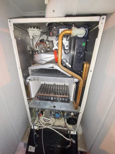 Açılmış kombi: eşanjör, brülör ve gaz valfi görünüyor